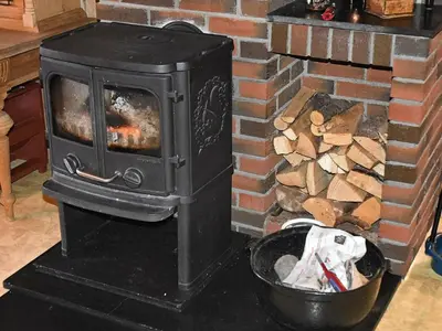 a stove with a pile of wood next to a brick fireplace at 8 person holiday home in EIDSVÅG in Eidsvåg