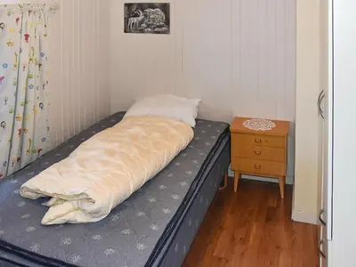 a bed in a corner of a room with a table at 8 person holiday home in EIDSVÅG in Eidsvåg
