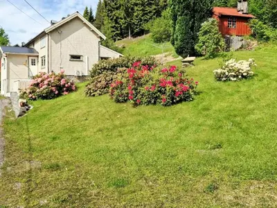 a green yard with flowers and a house at 8 person holiday home in EIDSVÅG in Eidsvåg