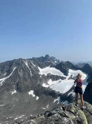 a woman standing on top of a mountain taking a picture at Nes Gard in Høyheimsvik