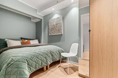 a bedroom with a bed and a white chair at Høyden Apartments in Bergen