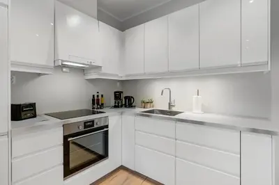 a white kitchen with white cabinets and a sink at Høyden Apartments in Bergen