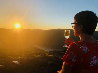 a woman holding a glass of wine at sunset at Grønset Skysstasjon in Vinjeøra
