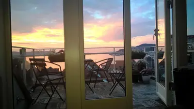 a view of a balcony with chairs and a sunset at Penthouse with perfect location and spectacular view in Bergen
