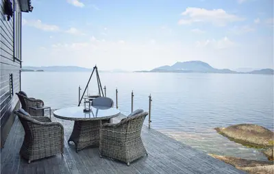 a patio with a table and chairs on the water at Lovely Home In Skånevik in Skånevik