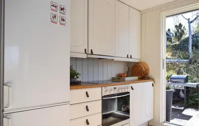 a kitchen with white cabinets and a window at Lovely Home In Skånevik in Skånevik