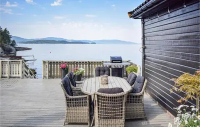a table and chairs on a deck with a view of the water at Lovely Home In Skånevik in Skånevik