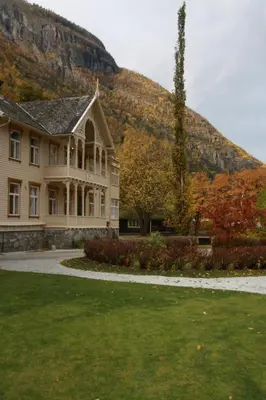 a large house with a mountain in the background at Lindstrøm Hotel in Lærdalsøyri