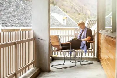 a man sitting on a rocking chair on a porch at Lindstrøm Hotel in Lærdalsøyri