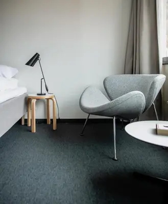a bedroom with a chair and a bed and a lamp at Lindstrøm Hotel in Lærdalsøyri