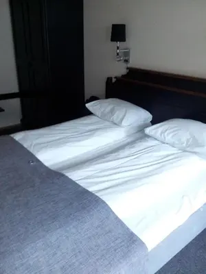 a large bed with white sheets and pillows at Motell Nor-Kro in Bromma