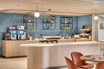 a restaurant with a counter and chairs and tables at Frichs Hotel Hamar in Hamar