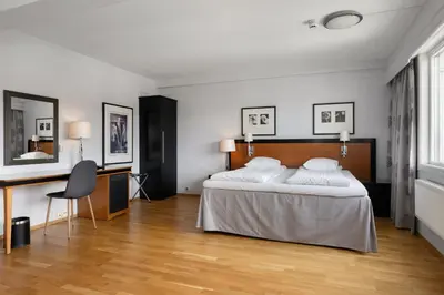 a bedroom with a large bed and a desk at Frichs Hotel Hamar in Hamar