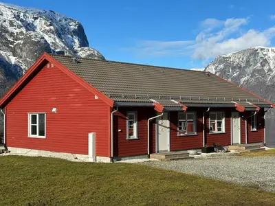 a red building with mountains in the background at Winjum Apartments Aurland Stegastein in Aurland