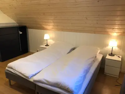 a bedroom with a bed with white sheets and two lamps at Balestrand Fjordapartments in Balestrand
