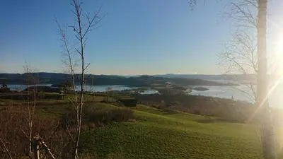 a view of a river from a hill with the sun shining at Husfrua Gårdshotell in Straumen