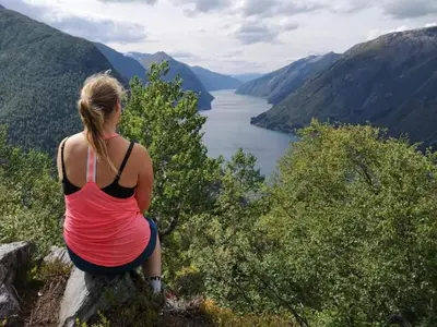 a woman sitting on a rock overlooking a lake at Sogndal ski- and mountain cabin in Sogndal