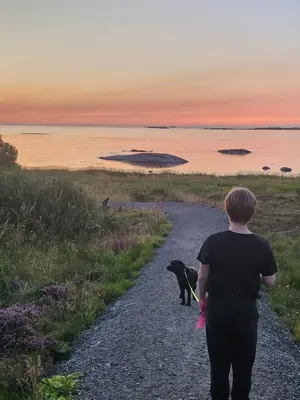 a woman walking a dog down a gravel road at Vestavind hytter og rom AS in Ålesund