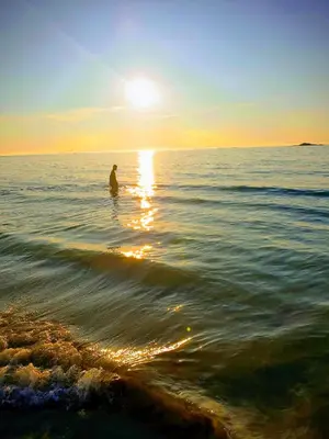 a man standing in the water at the beach at Vestavind hytter og rom AS in Ålesund