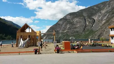 a playground on a beach next to a mountain at Lærdal Ferie- og Fritidspark in Lærdalsøyri