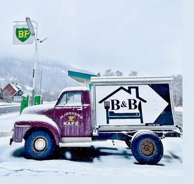 a red truck parked in the snow with a sign on it at Mjøsvang Kafe in Vang I Valdres
