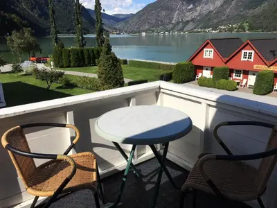 a table and chairs on a balcony with a view of a lake at Marifjøra Sjøbuer in Marifjora