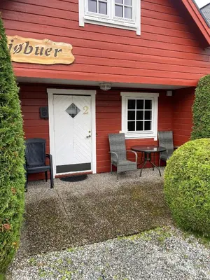 a red house with a patio with a table and chairs at Marifjøra Sjøbuer in Marifjora