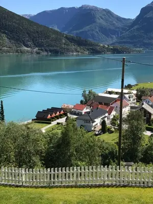 a village by the water with a white fence at Marifjøra Sjøbuer in Marifjora