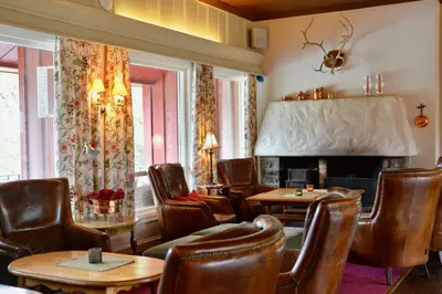 a restaurant with leather chairs and a fireplace at Vatnahalsen Høyfjellshotell in Myrdal