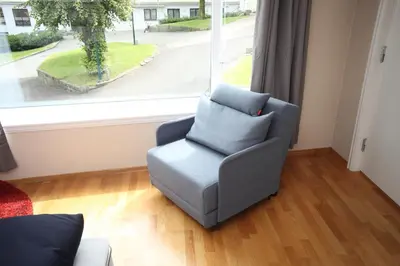 a chair in a living room with a window at Bergen's Best Location in Bergen