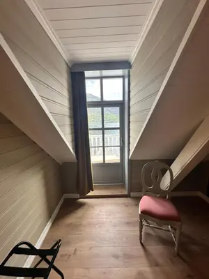 an attic room with a chair and a window at Hofslund Fjord Hotel in Sogndal