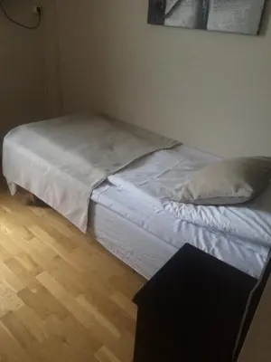 a unmade bed in a bedroom with a wooden floor at Nordfjord Hotell - Bryggen in Nordfjordeid