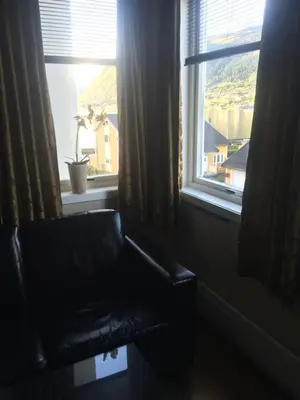 a black leather couch sitting in front of a window at Nordfjord Hotell - Bryggen in Nordfjordeid