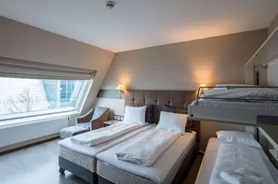 a bedroom with two beds and a chair and a window at Scandic Seilet Hotel in Molde