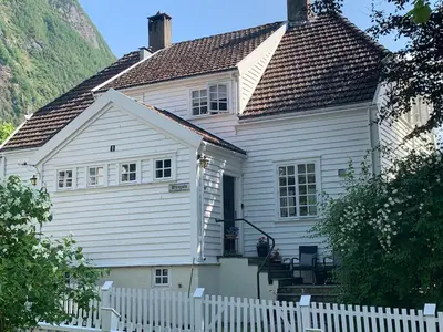 a white house with a white fence in front of it at Høyanger 3 roms leilighet in Høyanger