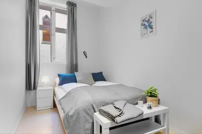a white bedroom with a bed and a table at Fabryka in Bergen