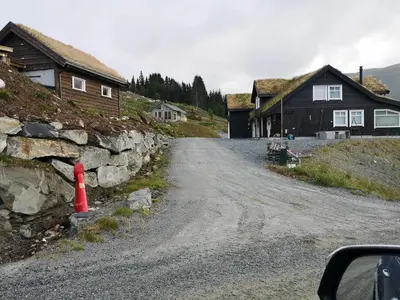 a dirt road in a village with houses and a red cone at Fjellsporthytta nr. 4 in Sogndal