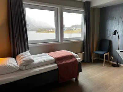 a bedroom with a bed and two large windows at Frichs Ekspress Åndalsnes in Åndalsnes