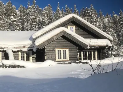 a cabin covered in snow with trees in the background at Kilen Lodge in Gaustablikk