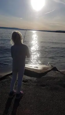 a young girl standing on the beach holding a fishing pole at Utvika Camping in Nes
