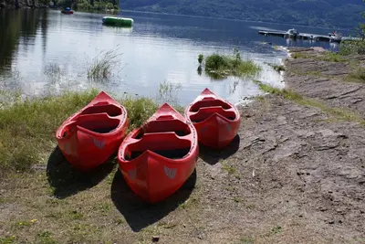 three red canoes sitting on the shore of a lake at Utvika Camping in Nes