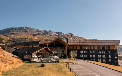 a large building with a mountain in the background at Fýri Resort in Hemsedal