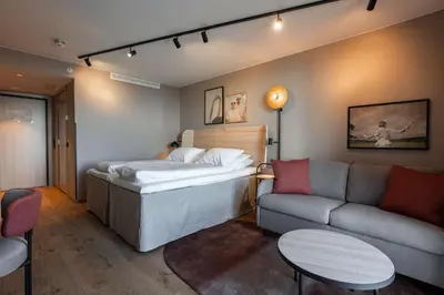 a bedroom with a bed and a couch and a table at Scandic Hamar in Hamar