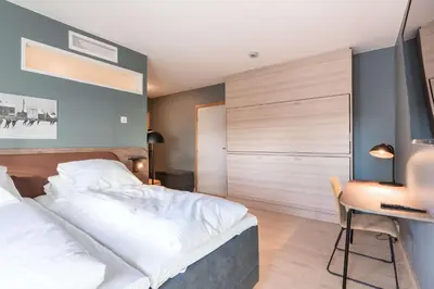 a bedroom with a large bed and a desk at Scandic Hamar in Hamar