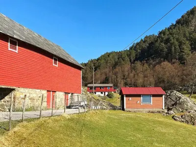 a red barn with a red roof next to a field at 9 person holiday home in Reksteren in Haukafer