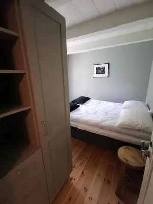 a small bedroom with a bed and a closet at Østigård 1810 in Åndalsnes