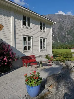 a house with a table and a bench and flowers at Østigård 1810 in Åndalsnes