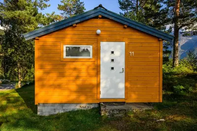 a small wooden shed with a door in the grass at Korsbakken Camping in Isfjorden
