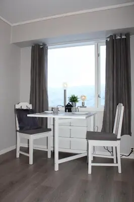 a white desk and two chairs in a room with a window at Studioleilighet i Haukedalen in Holsen