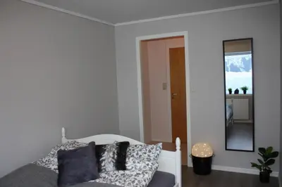 a bedroom with a white bed and a mirror at Studioleilighet i Haukedalen in Holsen